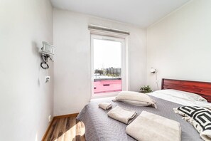 A bedroom with a bed, pillows, a bedside table, a window, and a view of the cityscape. - Top floor near ferry terminal. Free parking. (Tallinn)
