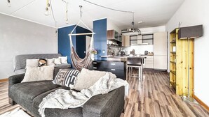 A modern living room with a sofa, a hanging chair, and a kitchen in the background. - Top floor near ferry terminal. Free parking. (Tallinn)