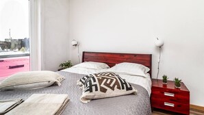 Une chambre à coucher avec un lit, des tables de chevet, une fenêtre et une vue sur l’extérieur.