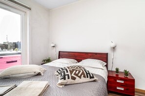 Een slaapkamer met een bed, nachtkastjes, een raam en uitzicht op het omliggende landschap.