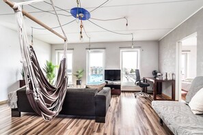 A modern living room with a hammock, a flat-screen TV, and a large window. - Top floor near ferry terminal. Free parking. (Tallinn)