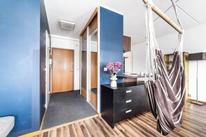 A room with a bed, a desk, a chair, a hanging hammock, and a vase with flowers. - Top floor near ferry terminal. Free parking. (Tallinn)