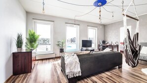 A modern bedroom with a large bed, a TV, and a hanging chair.