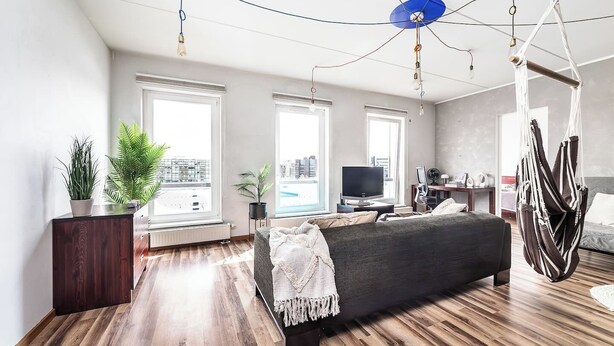 Une chambre moderne avec un grand lit, une télévision et un fauteuil suspendu.