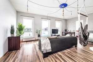 A modern bedroom with a large bed, a TV, and a hanging chair. - Top floor near ferry terminal. Free parking. (Tallinn)