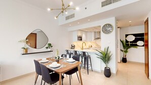 A modern kitchen with a central island, a dining area with a wooden table and chairs, and a large mirror on the wall.