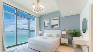 Een slaapkamer met een groot bed, een nachtkastje, een spiegel en uitzicht op zee.