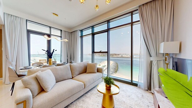 Een moderne woonkamer met een grote bank, een eettafel en uitzicht op zee.