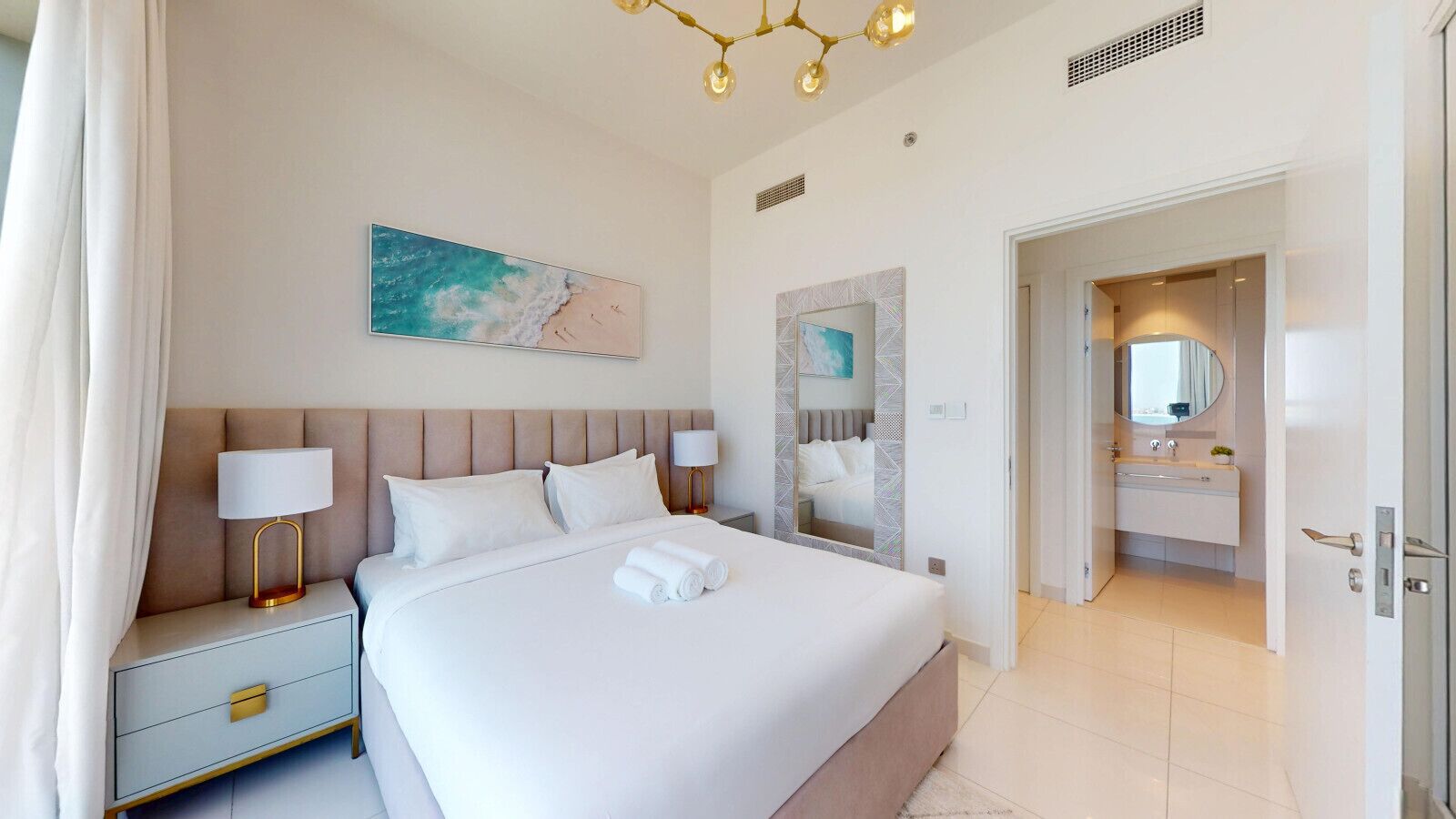 Una habitación de hotel moderna con una cama grande, mesitas de noche, un espejo y vistas al baño.