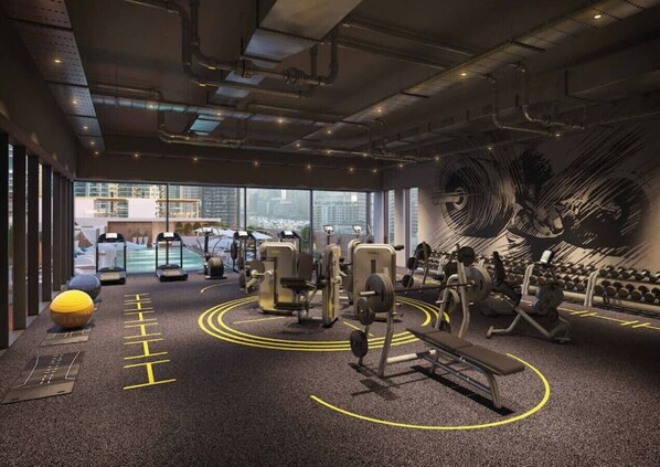 Ein Fitnessraum mit Trainingsgeräten, einem großen Fenster und Blick auf die Stadt.