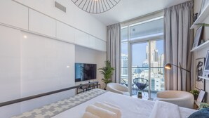 A modern hotel room with a large bed, a TV, a seating area, and a view of the city. - Cosy Studio l Aesthetic Finishes l Prime Location (Dubai Marina)