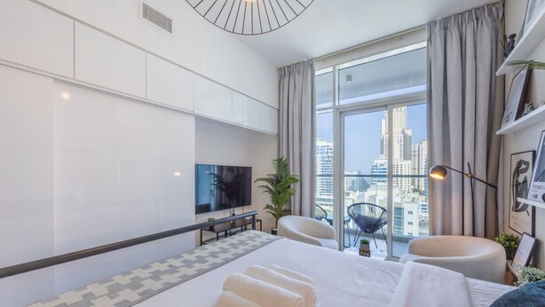 Une chambre d’hôtel moderne dotée d’un grand lit, d’une télévision, d’un coin salon et offrant une vue sur la ville.