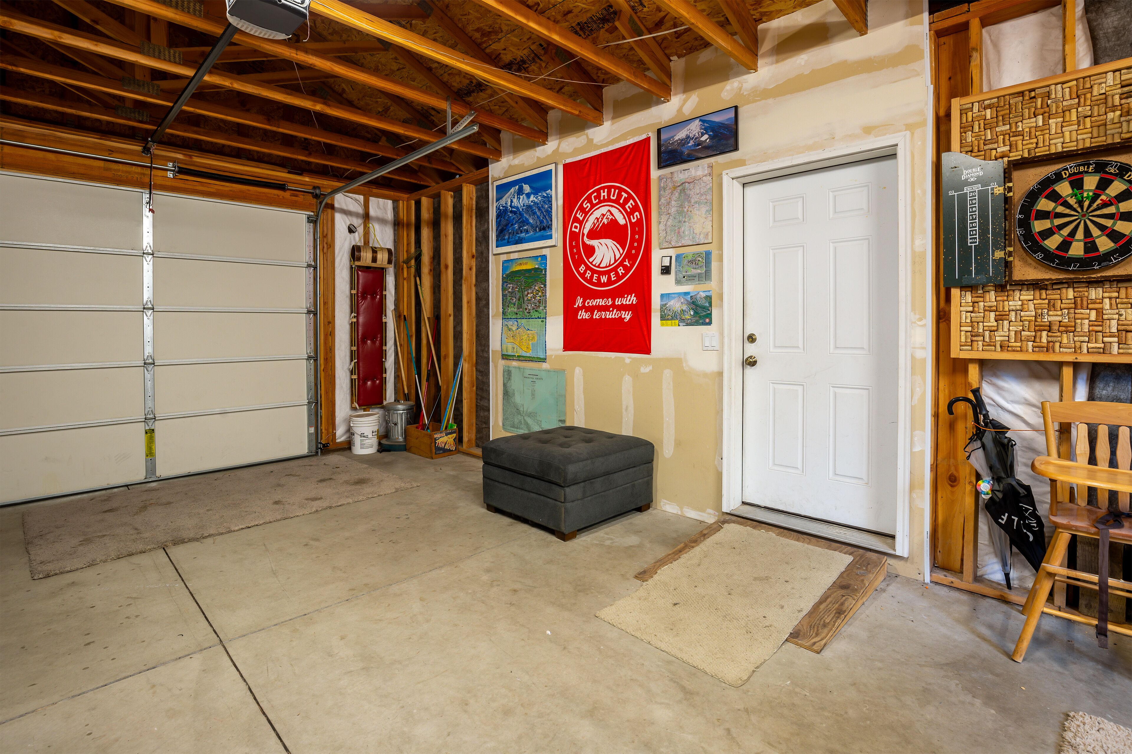 A garage with a wooden ceiling, a grey ottoman, and a dartboard on the wall.