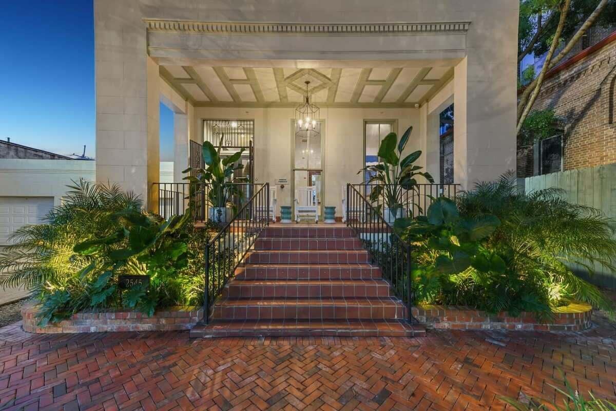 A building with a covered entrance, steps leading up to it, and a brick pathway.