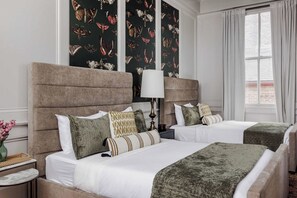 A hotel room with two beds, a nightstand, a lamp, and a window with curtains. - Grand 8BR NOLA Estate | Heated Pool & Spa (New Orleans)
