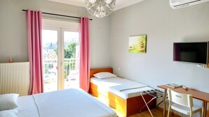 Een hotelkamer met twee bedden, een bureau met stoel, een televisie en uitzicht op het landschap.