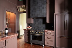 Una cuina amb una mosca decorativa de rajola marró fosc, una campana extractora d'acer inoxidable i un forn encastrat.