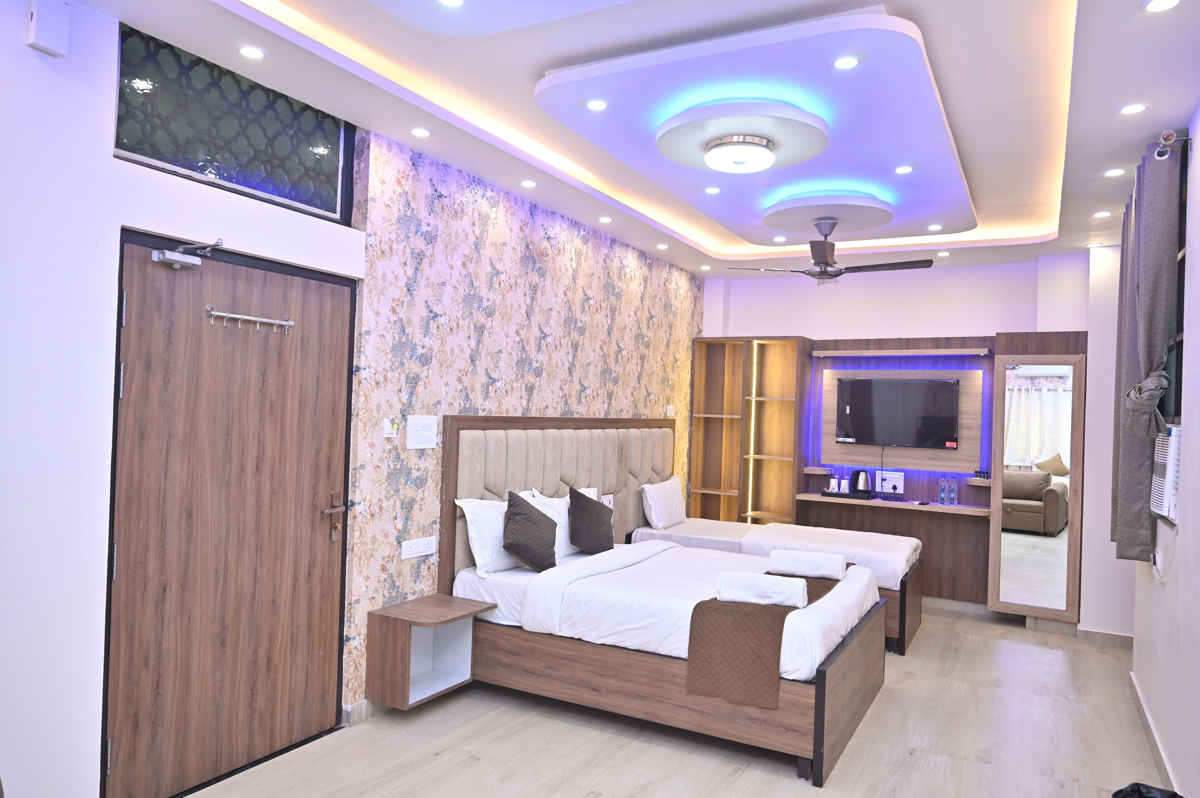 A modern bedroom with a large bed, bedside tables, a TV, and a ceiling fan.