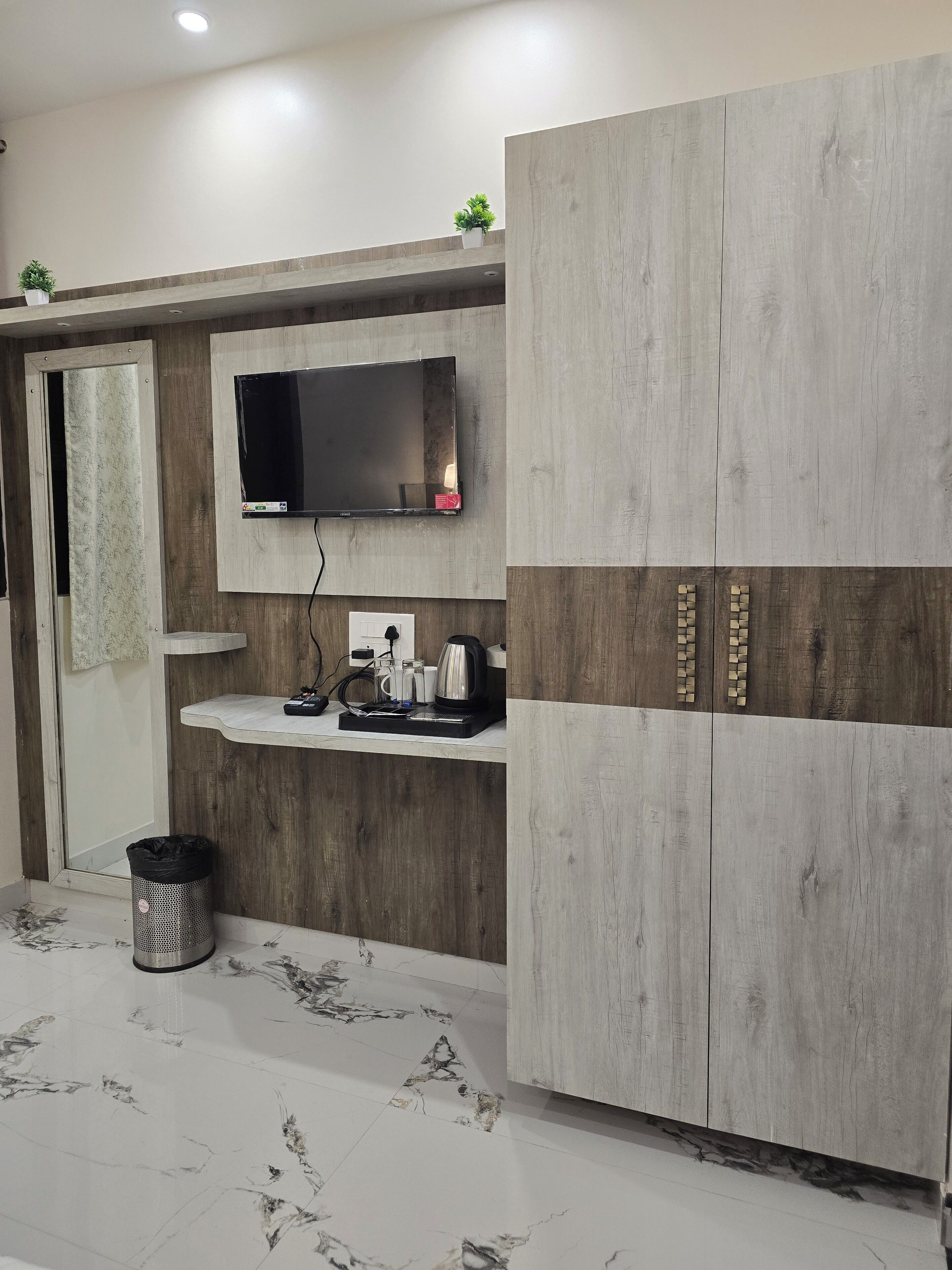 A modern bathroom with a large wardrobe, a mounted TV, and a sink with toiletries.