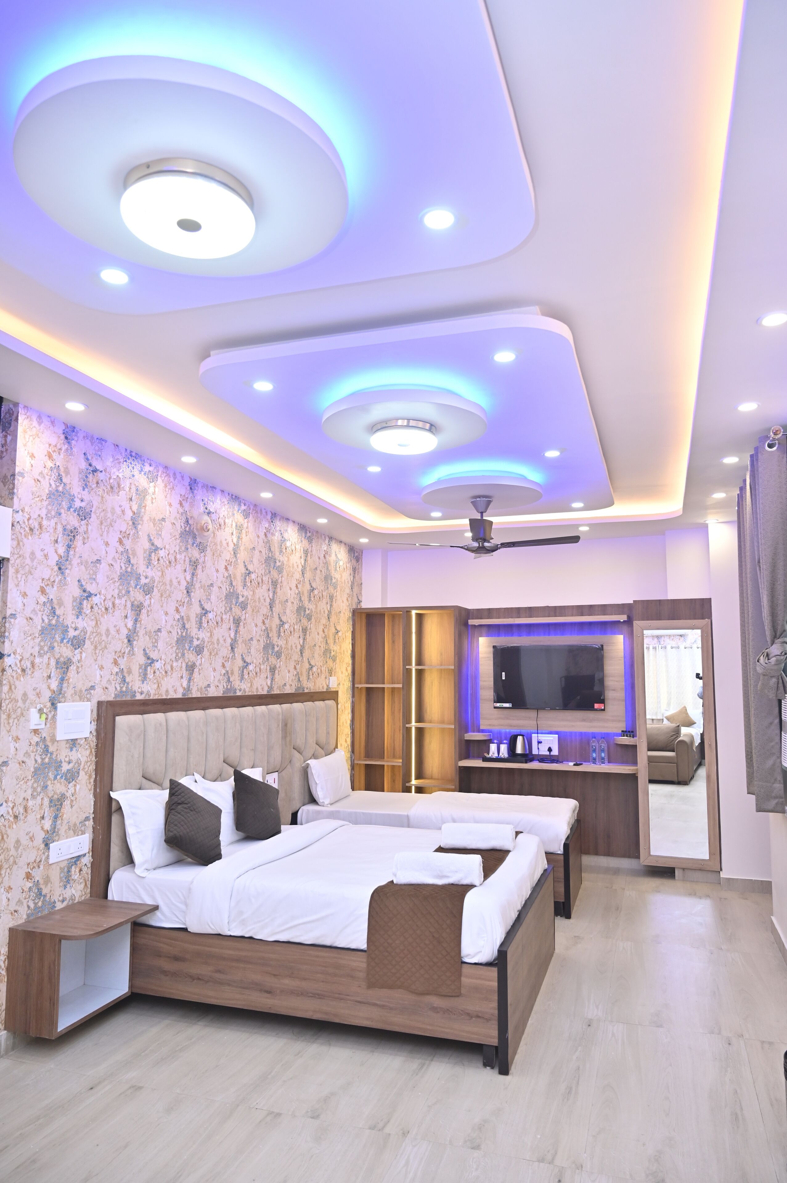 A modern bedroom with a large bed, a TV, and a ceiling fan.