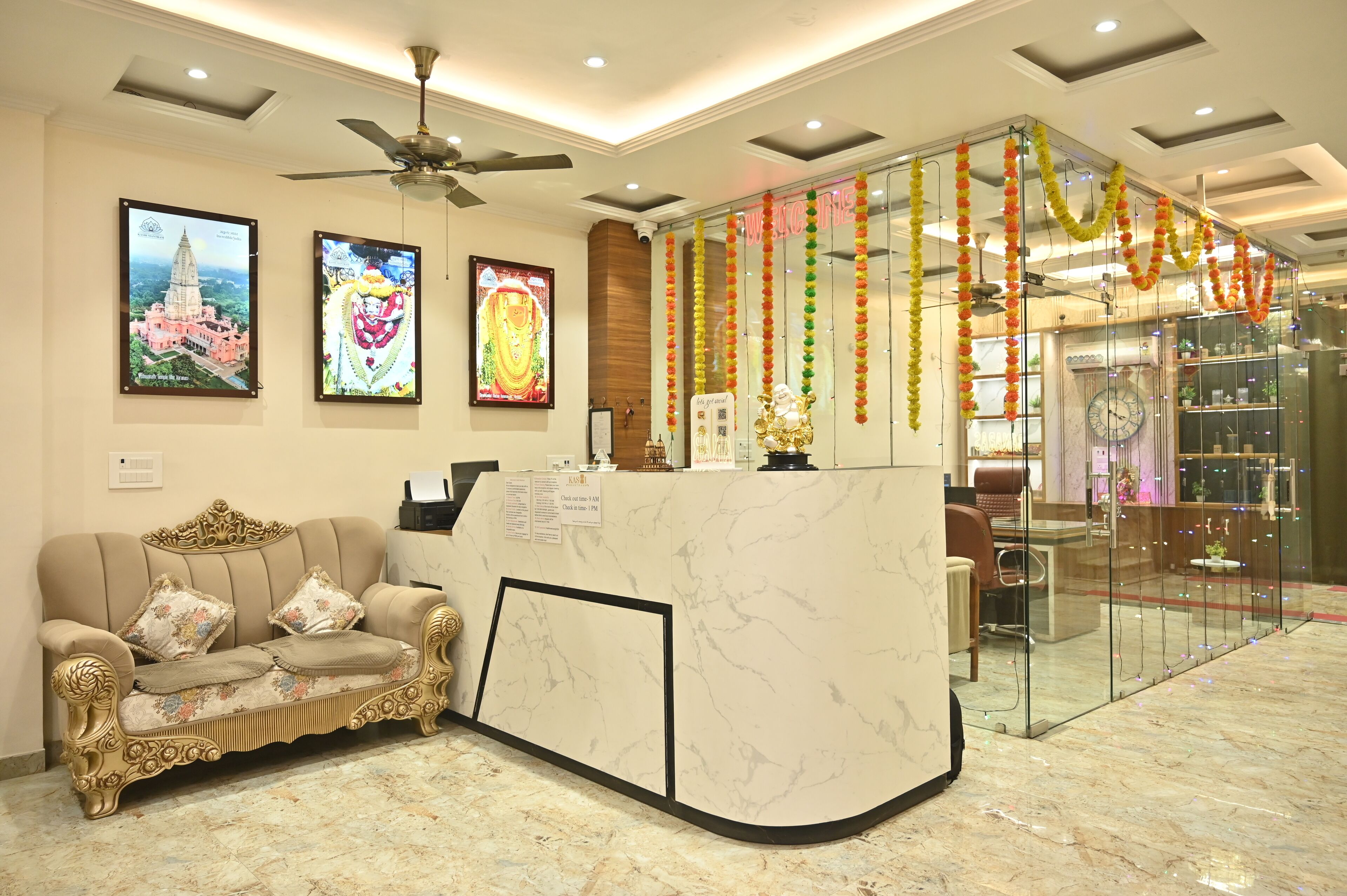 A reception area with a marble reception desk, a sofa, framed pictures on the wall, and a ceiling fan.