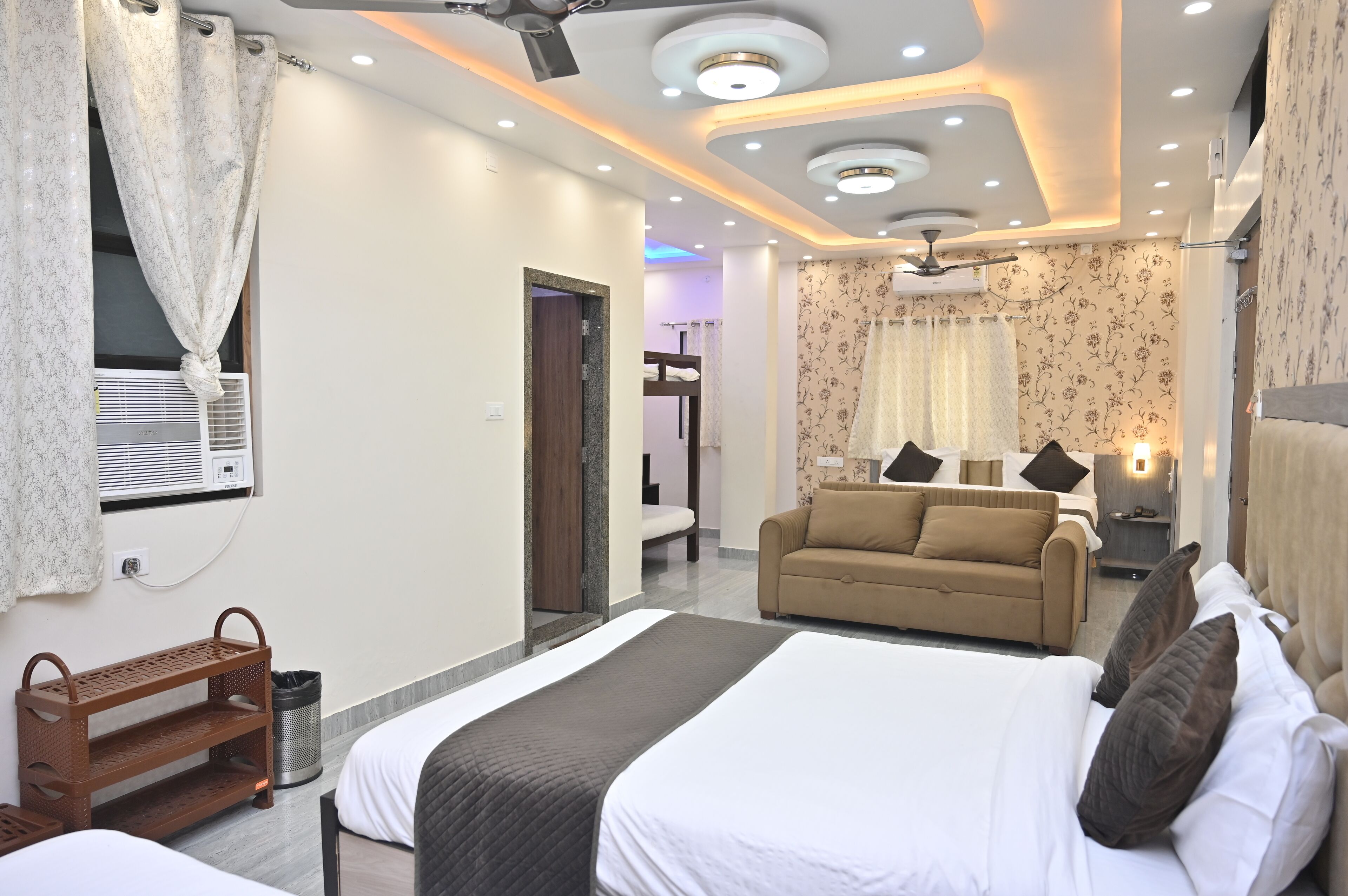 Una habitación de hotel con cama, sofá, una mesita y un ventilador de techo.