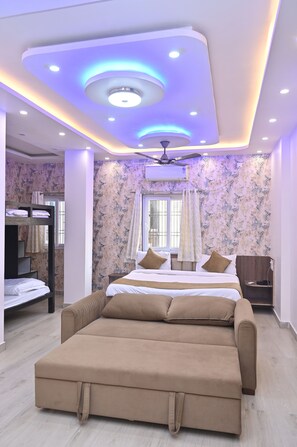 A modern bedroom with a large bed, a ceiling fan, and a bunk bed. - Hotel Kashi Mantram (Varanasi)