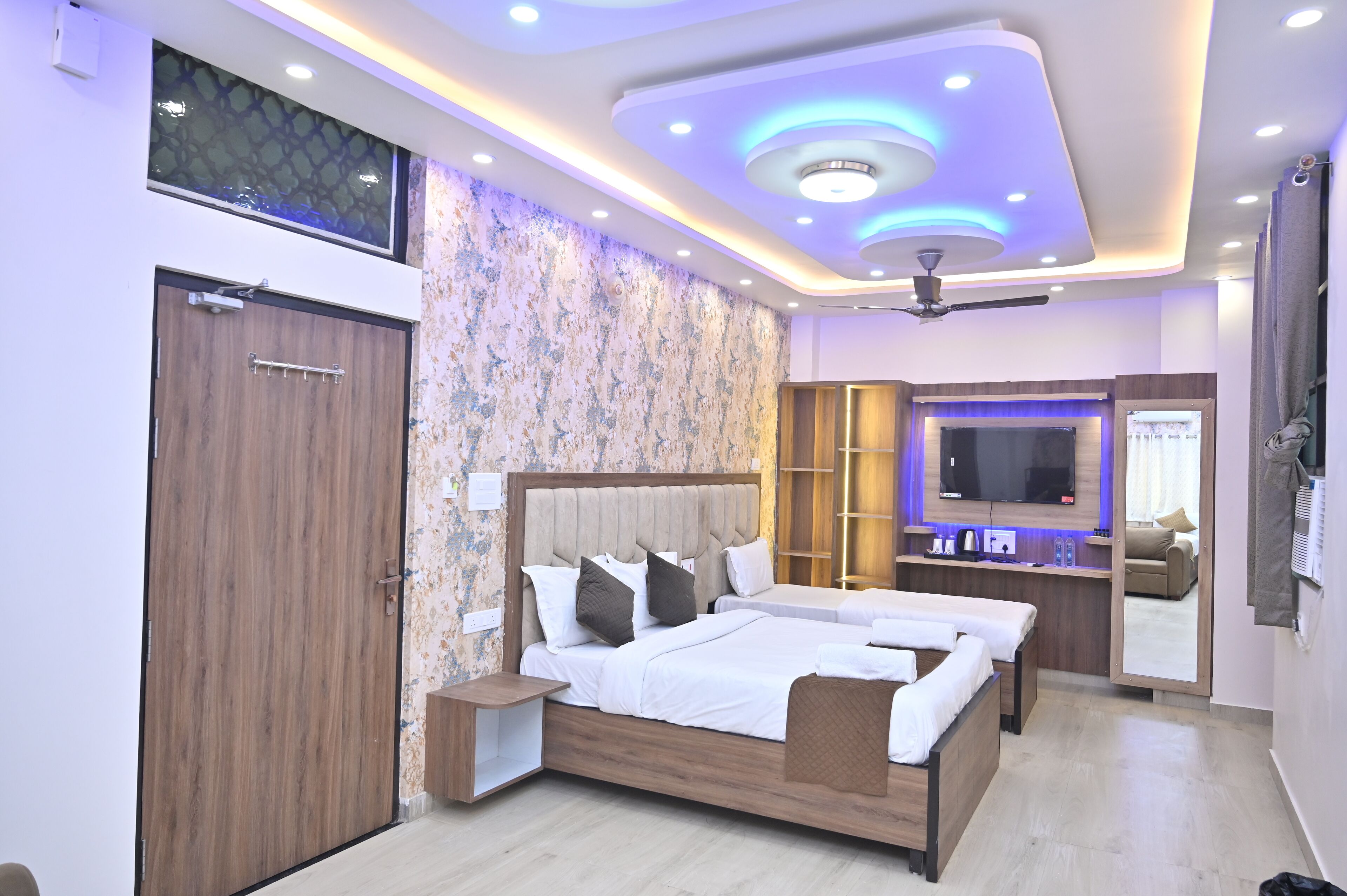 A modern bedroom with a large bed, a TV, a ceiling fan, and a built-in wardrobe.