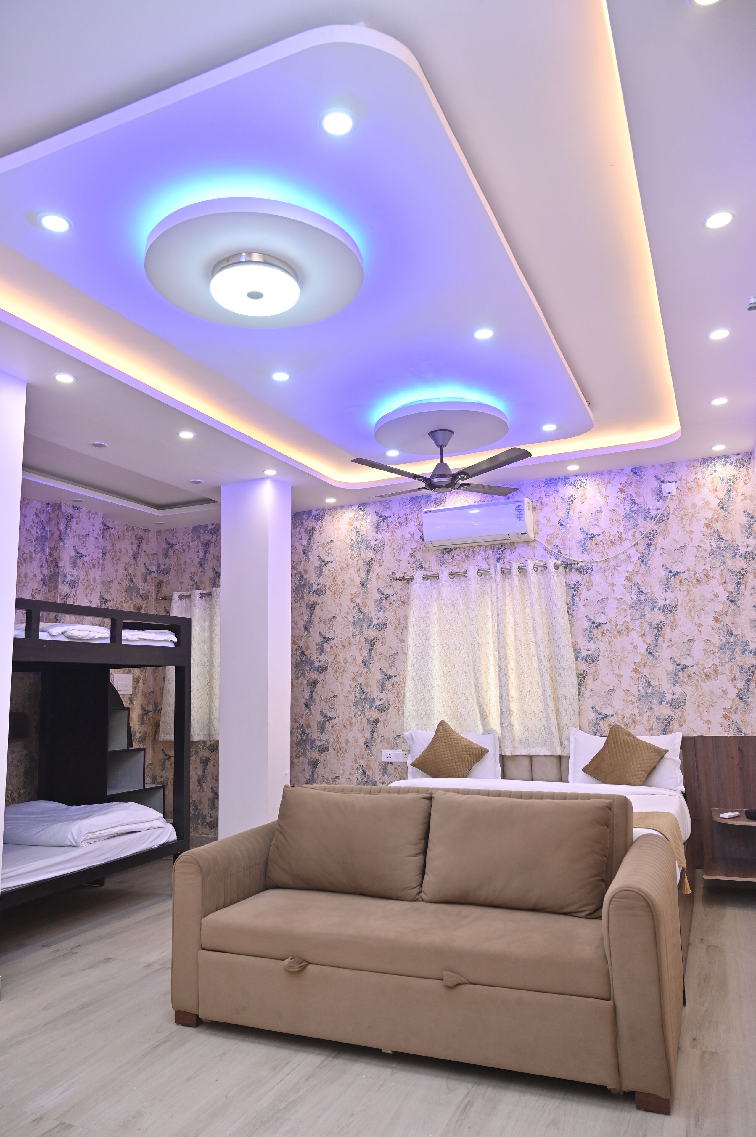A bedroom with a bunk bed, a sofa, a ceiling fan, and a bed with pillows.