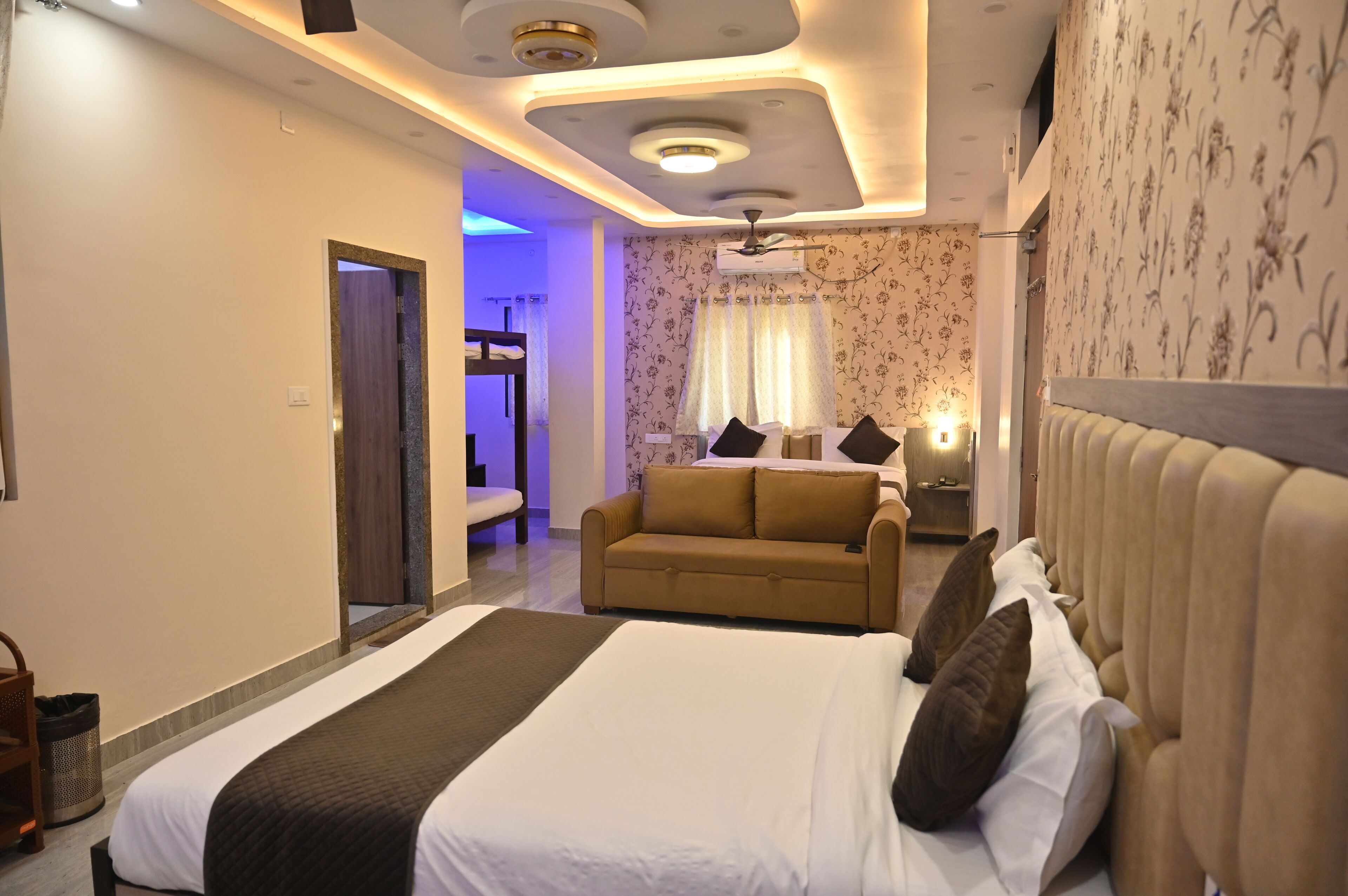 A hotel room with a large bed, a sofa, and a ceiling fan.