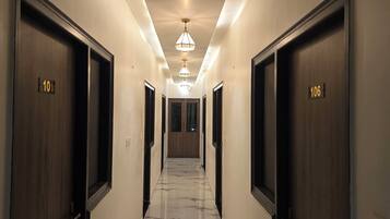 A hotel hallway with marble flooring, wooden doors numbered 101 and 106, and pendant lighting.