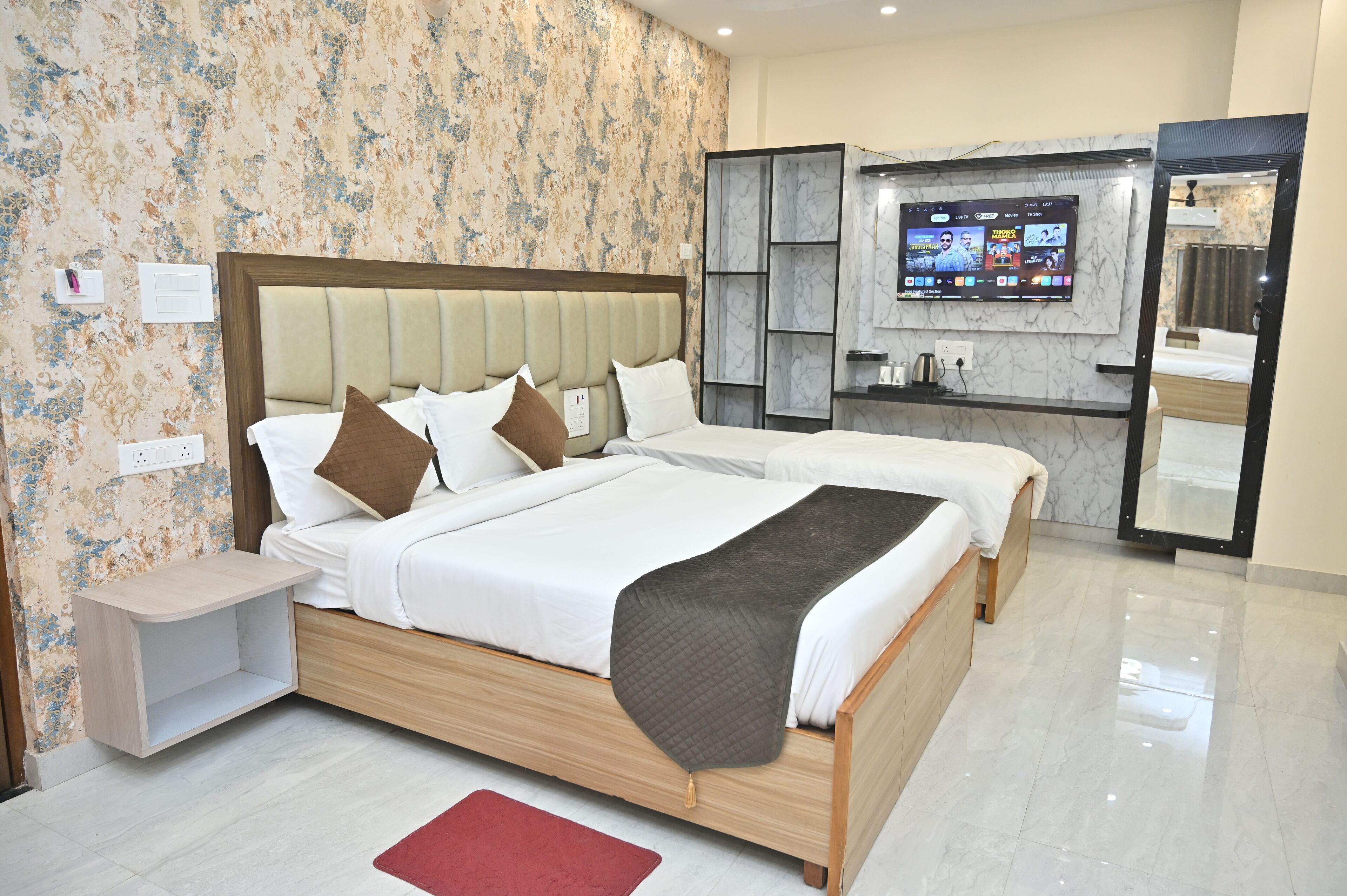 A modern hotel room with a large bed, a TV mounted on the wall, and a bathroom with a mirror and sink.