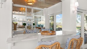 Una cocina moderna con armarios blancos, techo de madera y vista al exterior.