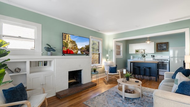 A living room with a fireplace, a dining area, and a kitchen.