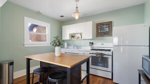 A kitchen with a wooden island, bar stools, a white refrigerator, and a stove.