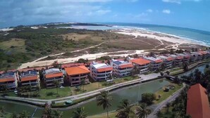 A coastal resort with multiple buildings featuring red roofs, a beach, and a body of water.