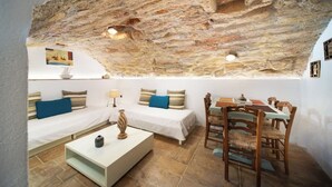 Une pièce chaleureuse avec un plafond en pierre rustique, un lit, un canapé, une table à manger avec des chaises et une table basse.