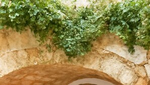 A stone archway leading to a door, a small table, and a chair in a courtyard. - Menexes Suites Fiorelli Suite with Garden View (Monemvasia)
