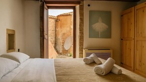 A bedroom with a bed, a wooden wardrobe, and a painting on the wall. - Menexes Suites Fiorelli Suite with Garden View (Monemvasia)