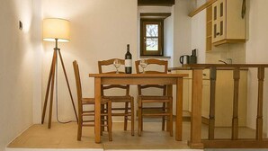 A rustic dining area with a wooden table, chairs, a floor lamp, and a staircase leading to an upper level. - Menexes Suites Fiorelli Suite with Garden View (Monemvasia)