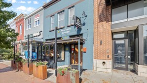 Une vue de rue avec un immeuble bleu portant l’inscription « Hill East Burger » et, de l’autre côté de la rue, les bureaux d’un service d’aide juridique.