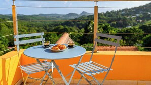 A balcony with a round table and chairs, a plate of food, and a cup of coffee. - Villa Caryota | Mountain Panorama & 29ft (9m) Private Pool (le Marin)