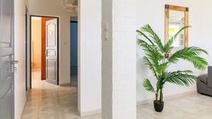 A hallway with a potted plant, a wooden-framed mirror, and a door leading to another room. - Villa Caryota | Mountain Panorama & 29ft (9m) Private Pool (le Marin)