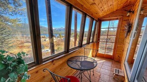 Una cabaña de madera con ventanas grandes que ofrece vistas a un paisaje montañoso.