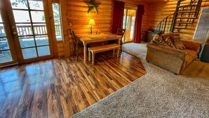 Interior de una cabaña de troncos con una mesa de comedor de madera, una decoración con forma de estrella y una escalera.