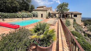Una villa de piedra con piscina, zona de estar al aire libre y vistas al paisaje.