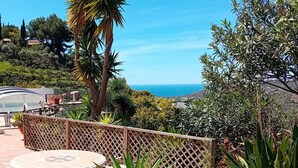 A patio with a round table and chairs, surrounded by various plants and a view of the sea. - Andalusian finca with private pool, sea views and stunning sunsets (Torrox)