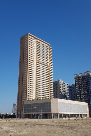 A tall, modern building with a geometric facade and a flat roof. - Elegant 2BR in Tower 108 Jumeirah Village Circle by Deluxe Holiday Homes (Dubai)