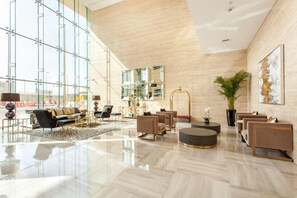 A spacious lobby with a high ceiling, large windows, and a modern interior design.