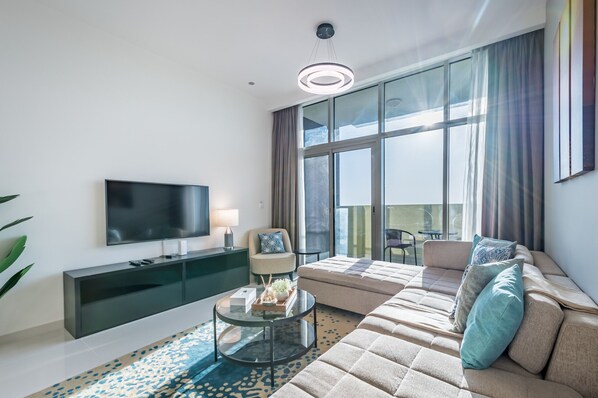 A modern living room with a large flat-screen TV, a sofa, a coffee table, and a glass cabinet.